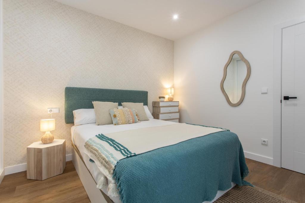 um quarto com uma cama grande e um espelho em Zalaeta Playa Apartments em La Coruña
