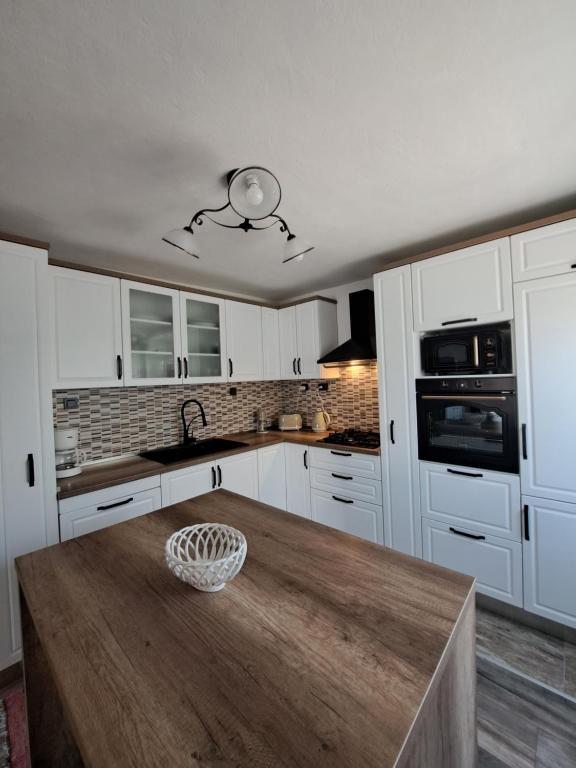 a kitchen with white cabinets and a wooden table at Apartman Prošperino in Vis