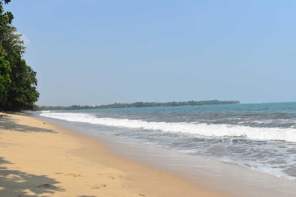 uma praia de areia com o oceano num dia ensolarado em Condo In Carita - 9202B em Carita