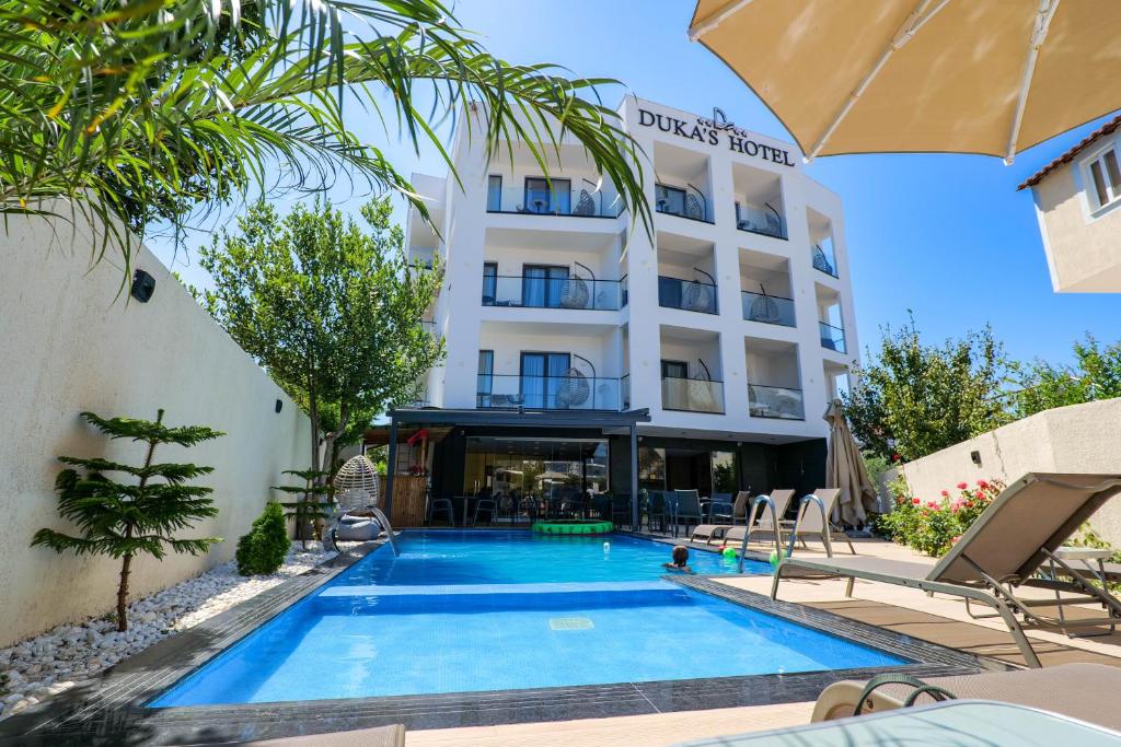 a hotel with a swimming pool in front of a building at Duka's Hotel in Ksamil