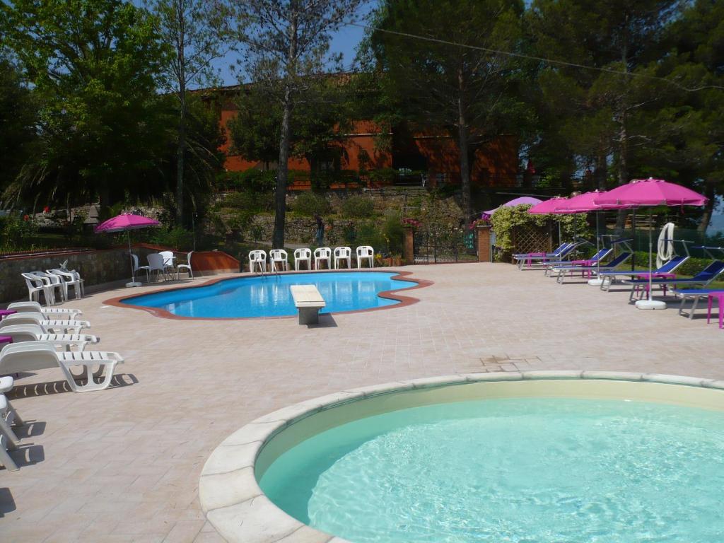 basen z krzesłami, stołami i parasolami w obiekcie Hotel Il Poggetto w mieście Castellina Marittima