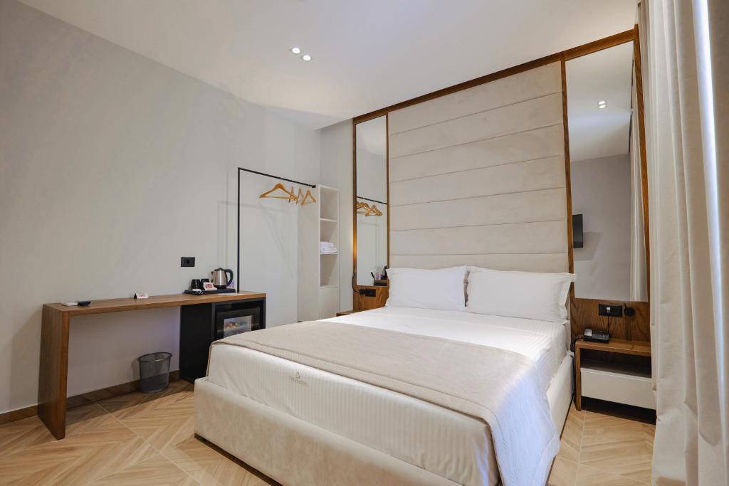 a bedroom with a large white bed and a desk at Duka's Hotel in Ksamil