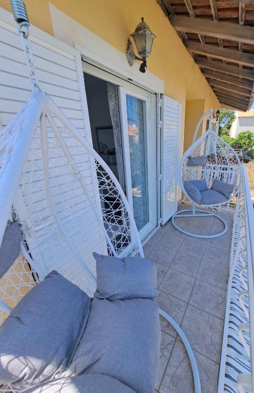 a porch with a swing and a chair at Apartman Prošperino in Vis