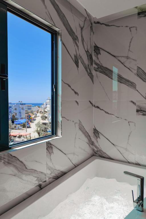 a bathroom with a bath tub and a window at Duka's Hotel in Ksamil