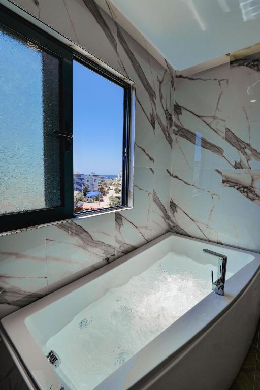 a bathroom with a bath tub with a window at Duka's Hotel in Ksamil