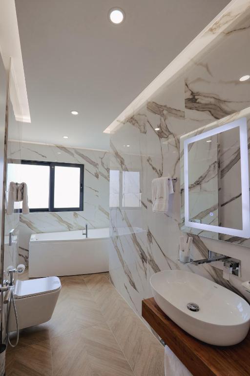 a white bathroom with a sink and a mirror at Duka's Hotel in Ksamil