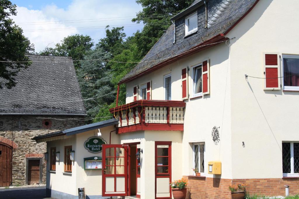 a white building with red doors and a balcony at Landgasthaus Alter Posthof in Halsenbach