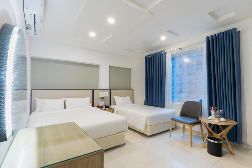 una habitación de hotel con 2 camas y una silla en A25 Hotel - 14 Lương Hữu Khánh, en Ho Chi Minh