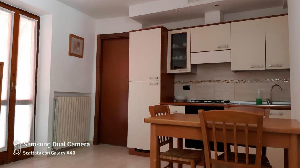 eine Küche mit einem Holztisch und Stühlen sowie einem Tisch und Schränken in der Unterkunft Appartamento Le Cascate 1° Piano in Cittiglio