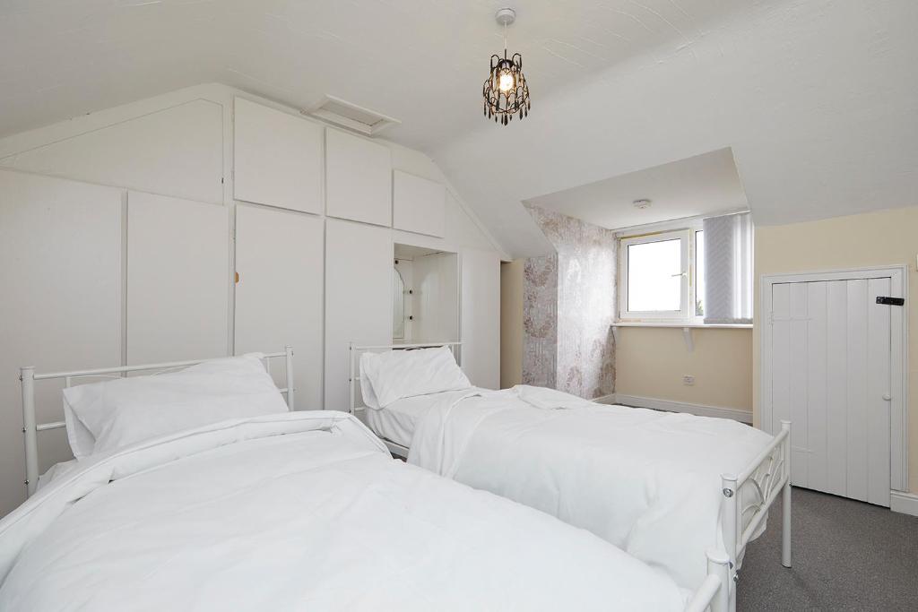 Habitación blanca con 2 camas blancas y lámpara de araña. en Comfortable 4-Bed House in Hucknall Nottingham, en Nottingham