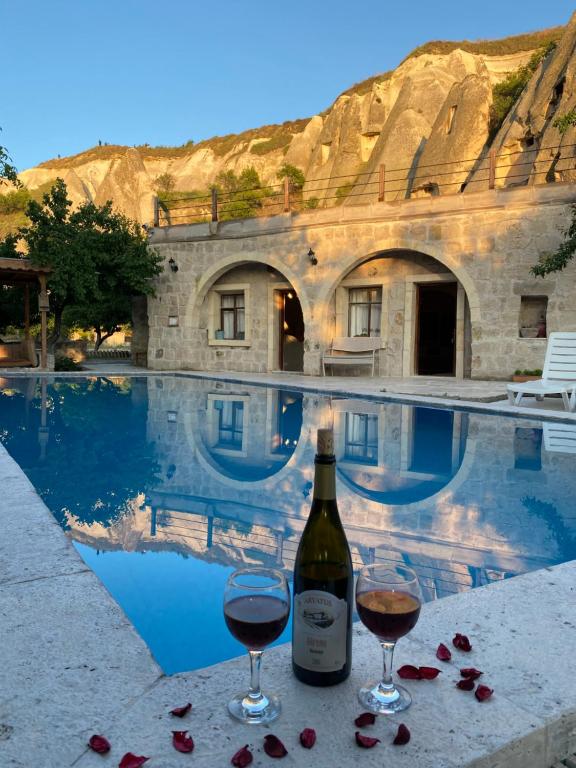 a bottle of wine and two glasses next to a swimming pool at Seven Rock Cave Hotel in Goreme