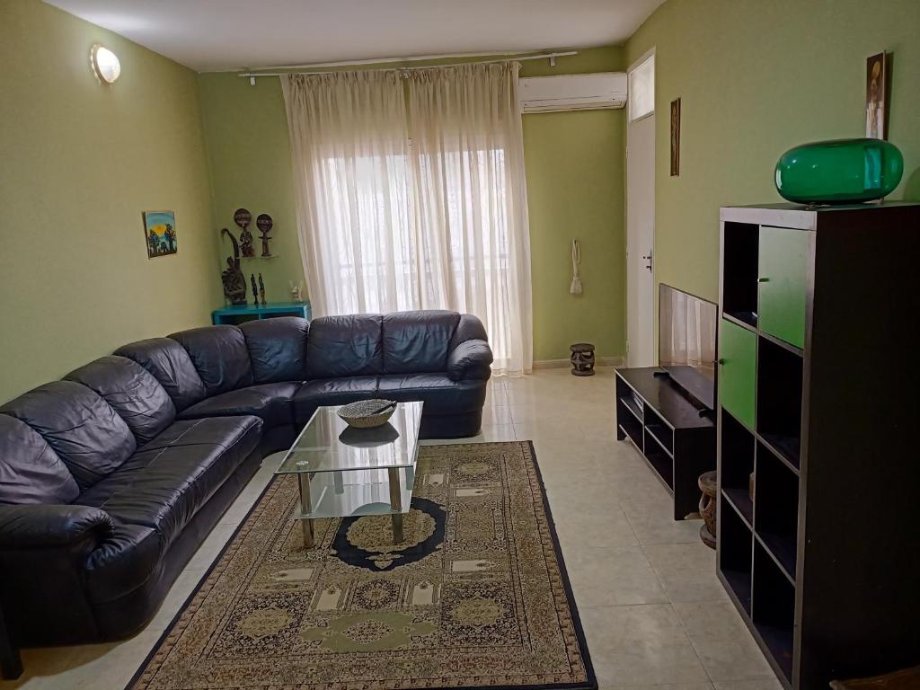 sala de estar con sofá de cuero y mesa en Appartement 2 chambres Yoff Virage Dakar Senegal en Dakar