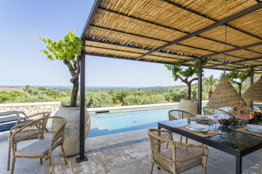 a patio with a table and chairs and a pool at Villa Silente - IsulaTravel in Noto