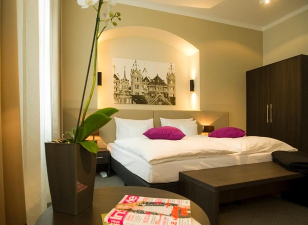 2 Betten in einem Hotelzimmer mit lila Kissen in der Unterkunft Hotel Residenz am Königsplatz in Speyer