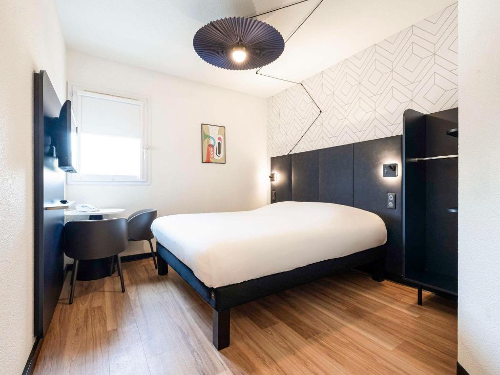 Schlafzimmer mit einem Bett, einem Schreibtisch und einem Waschbecken in der Unterkunft ibis Perpignan Sud Saint Charles in Perpignan