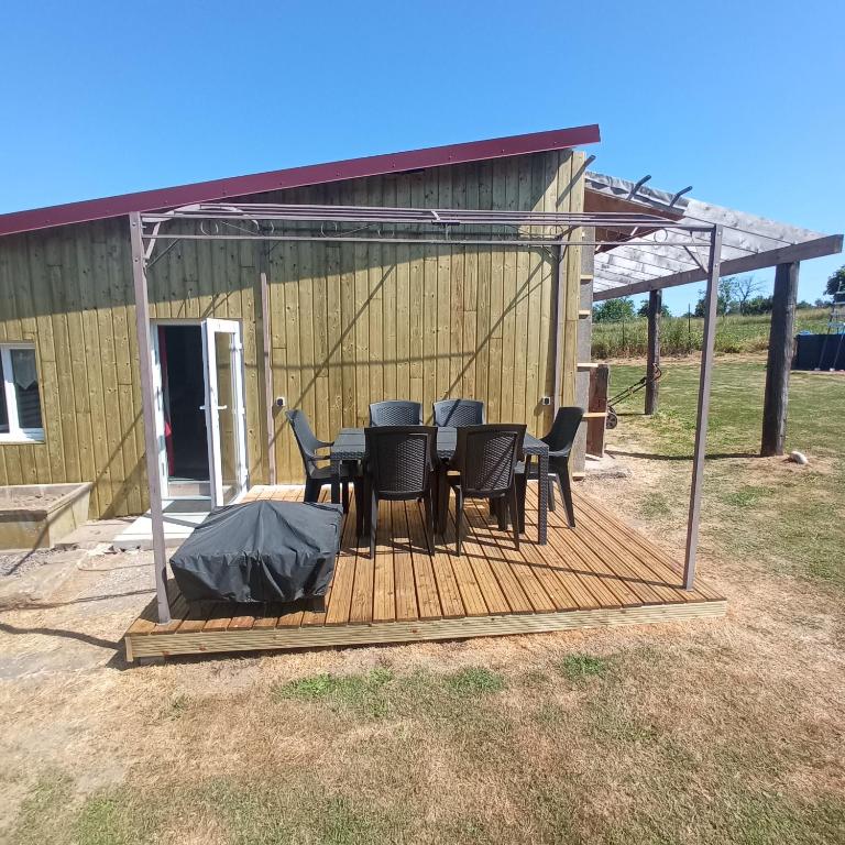 une terrasse en bois avec une table et des chaises dessus dans l'établissement Maison d'hôtes A la fontaine fleurie 88, à Frémifontaine