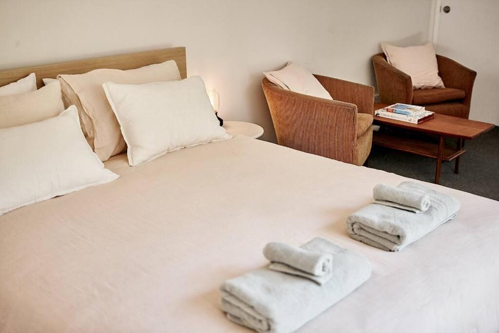 a bedroom with a white bed with towels on it at Cosy hillside studio in Ocean Shores