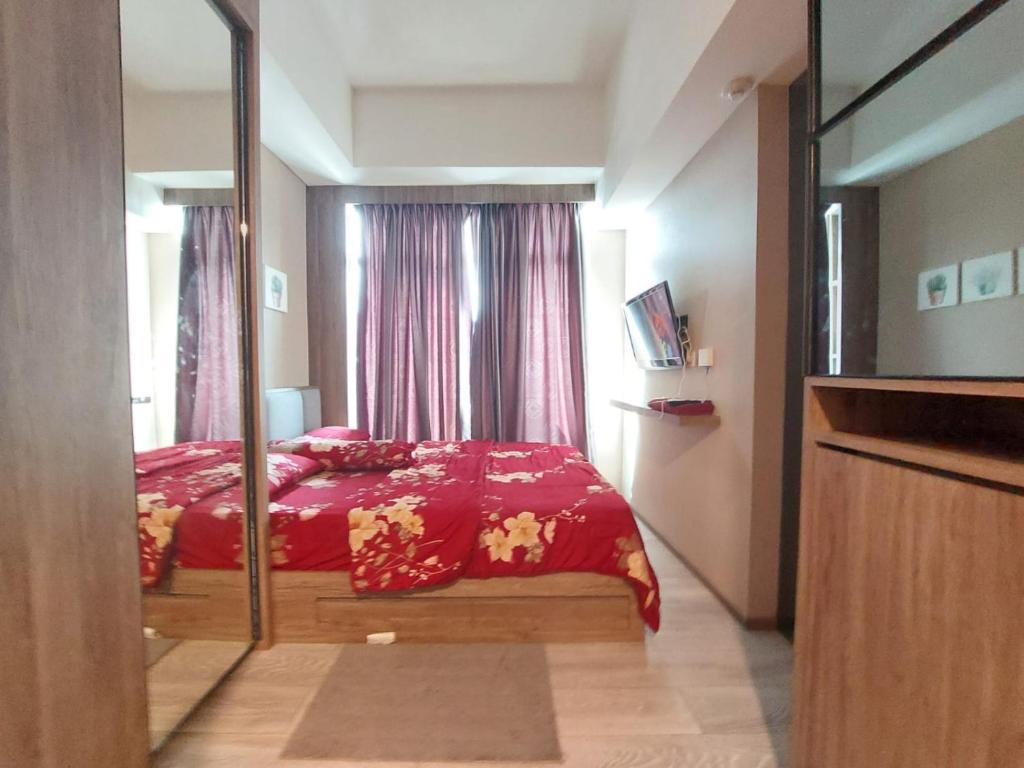 1 dormitorio con cama roja y espejo en Ilham Apartemen Batch 1, en Serang