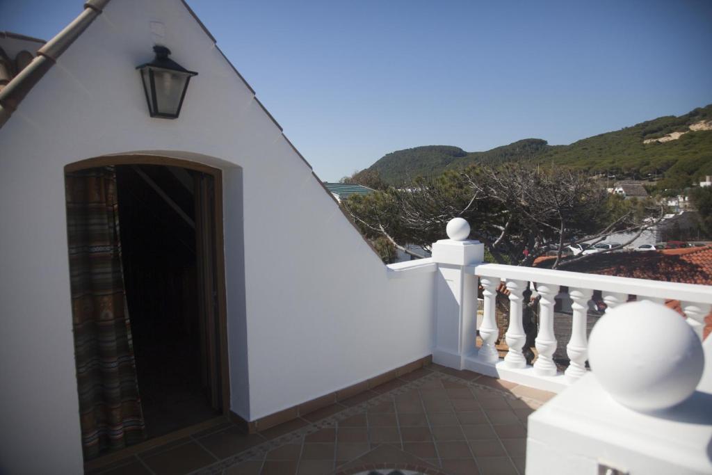 a white house with a door and a balcony at Hostal Mar de Frente in Los Caños de Meca
