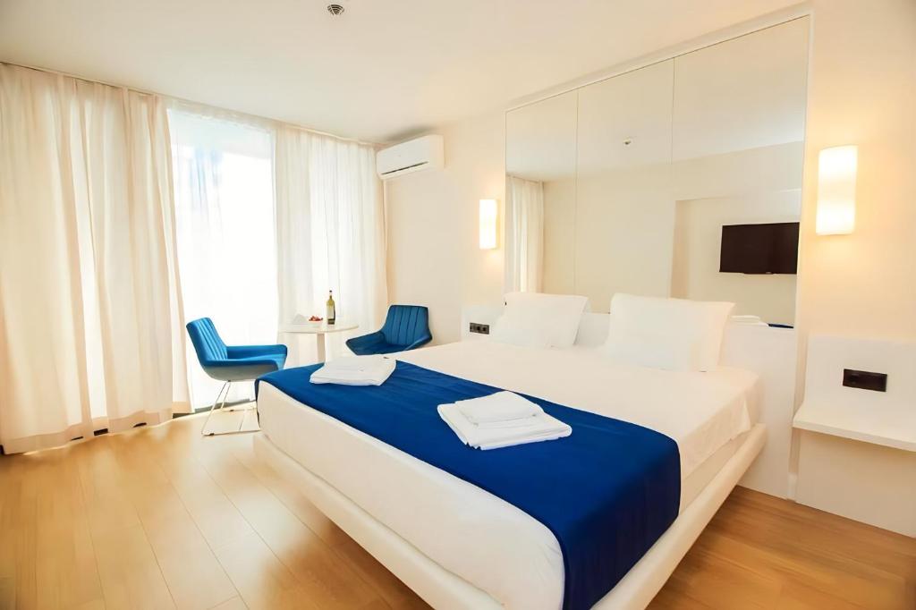 a bedroom with a large bed and two blue chairs at ORBI CITY lux studio apartment in Batumi