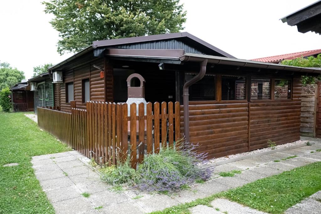 una cabaña de madera con una valla delante en Hiška Amoris K117 Terme Banovci, 2 kopalni karti gratis, en Veržej