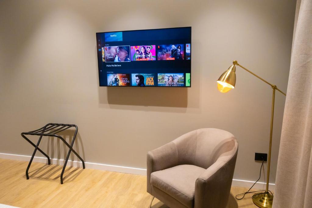 a living room with a chair and a tv on a wall at Bee Hotel in Vlorë