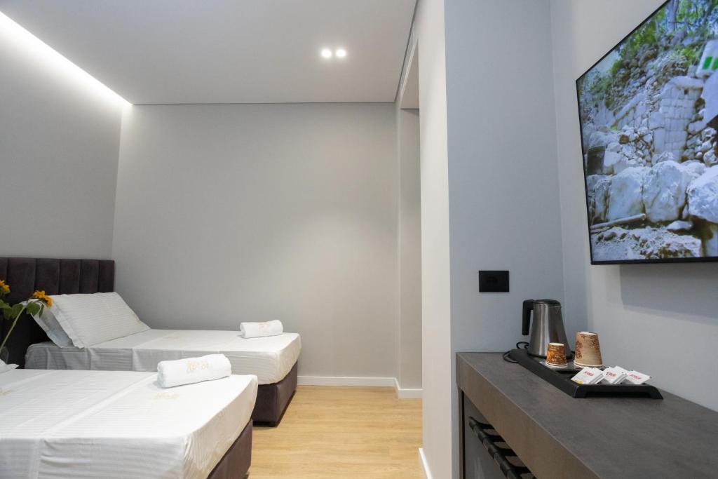a room with two beds and a flat screen tv at Bee Hotel in Vlorë