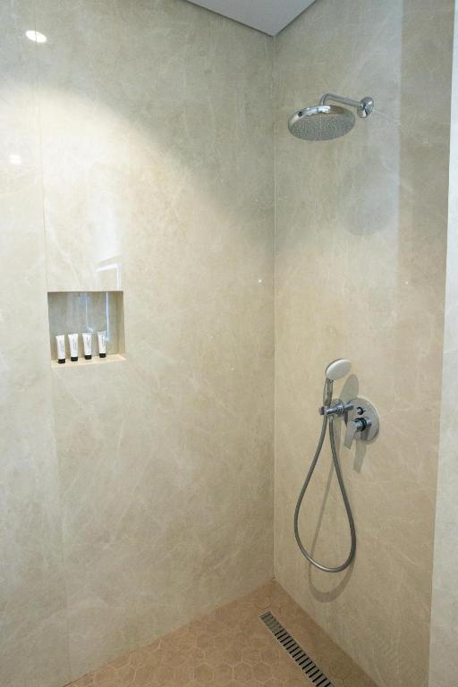 a shower with a shower head in a bathroom at Bee Hotel in Vlorë