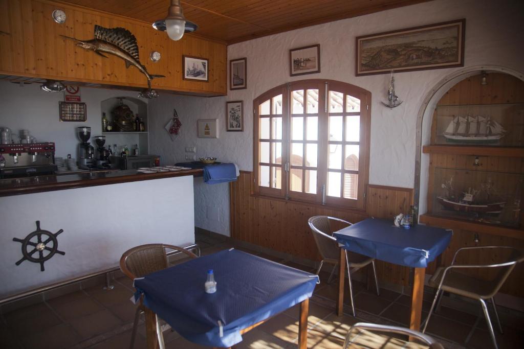 a restaurant with two blue tables and a kitchen at Hostal Mar de Frente in Los Caños de Meca