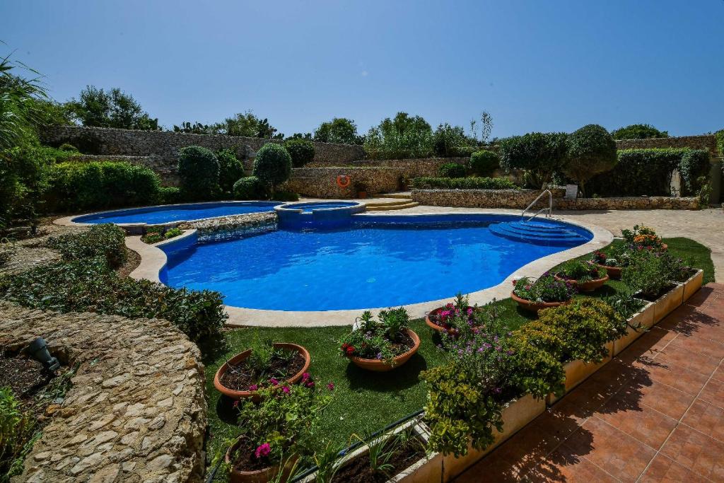 einen Pool in einem Garten mit Topfpflanzen in der Unterkunft Gozo Spacious Apartment with Large Communal Pool in Qala