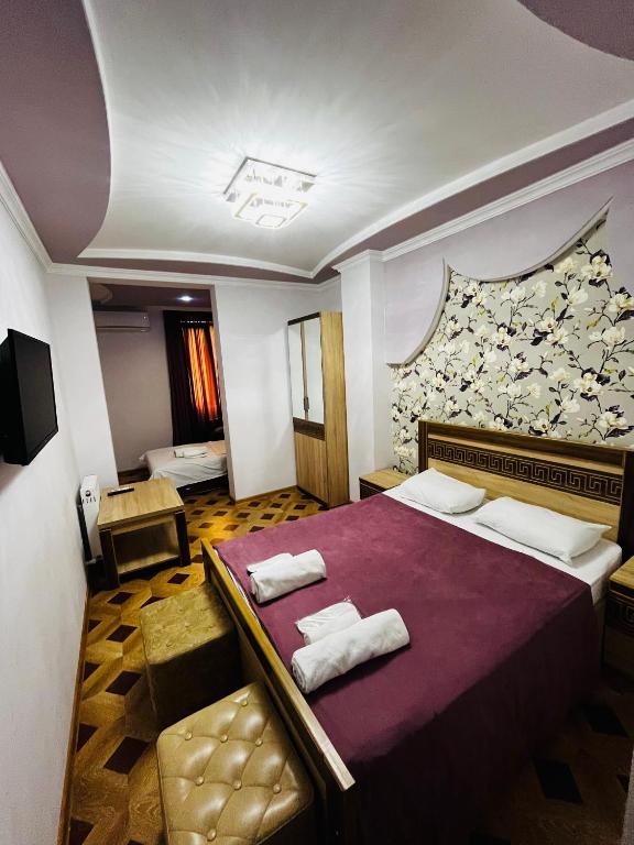 a bedroom with a purple bed with two towels at Georgian Palace Hotel in Kutaisi