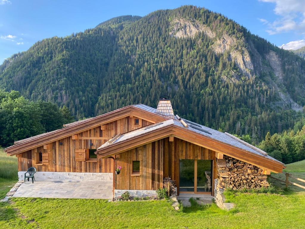 uma cabana de madeira com uma montanha ao fundo em chalet du Champel jacuzzi em Saint-Gervais-les-Bains