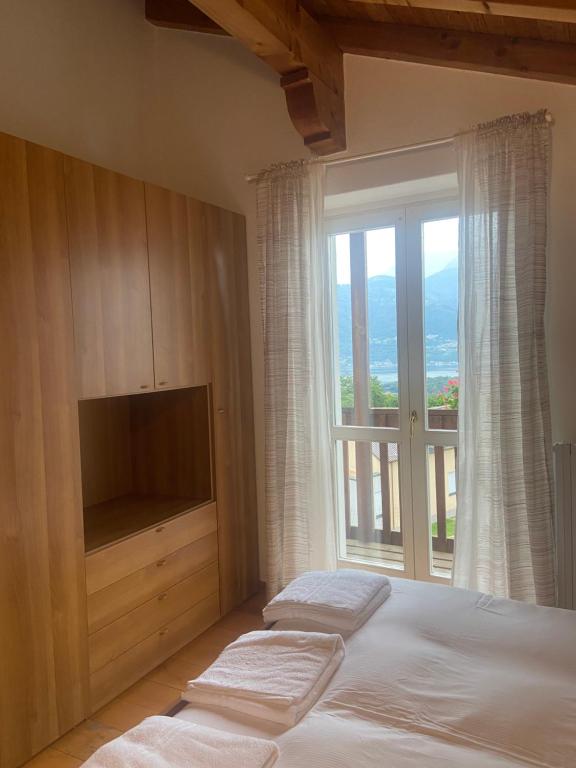Schlafzimmer mit einem Bett, einem TV und einem Fenster in der Unterkunft Casa Camilla in Colico