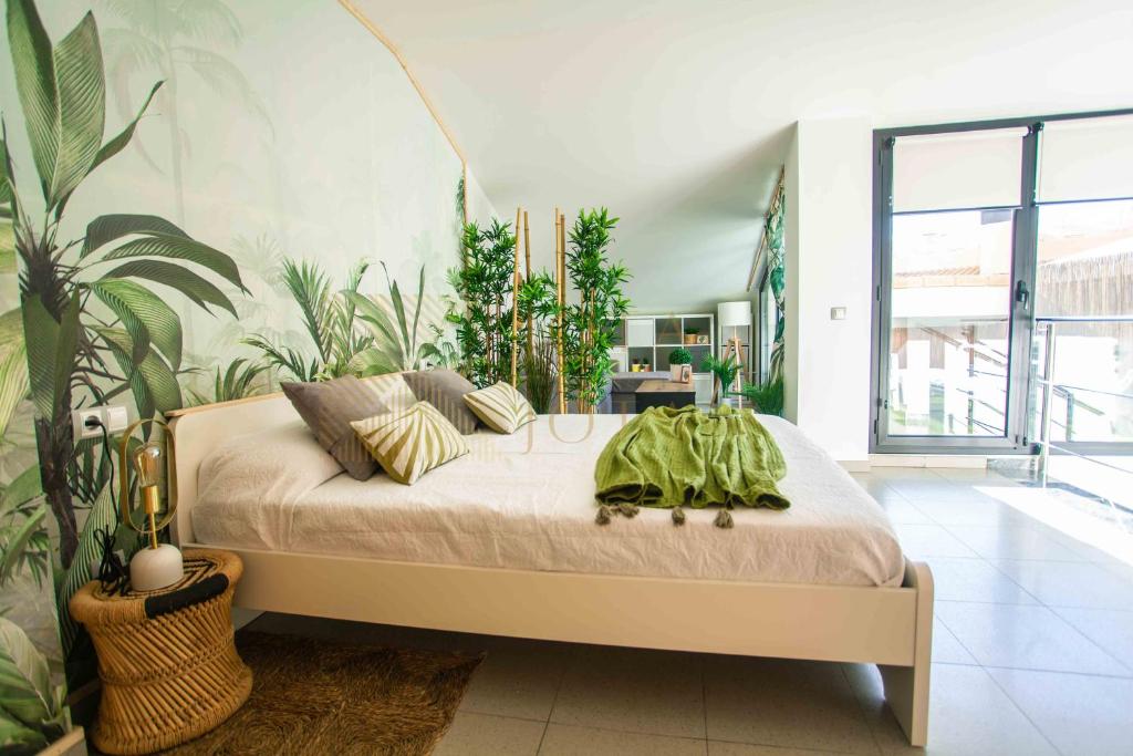 een slaapkamer met een bed in een kamer met planten bij Duplex LUX Jota Jota in Lloret de Mar
