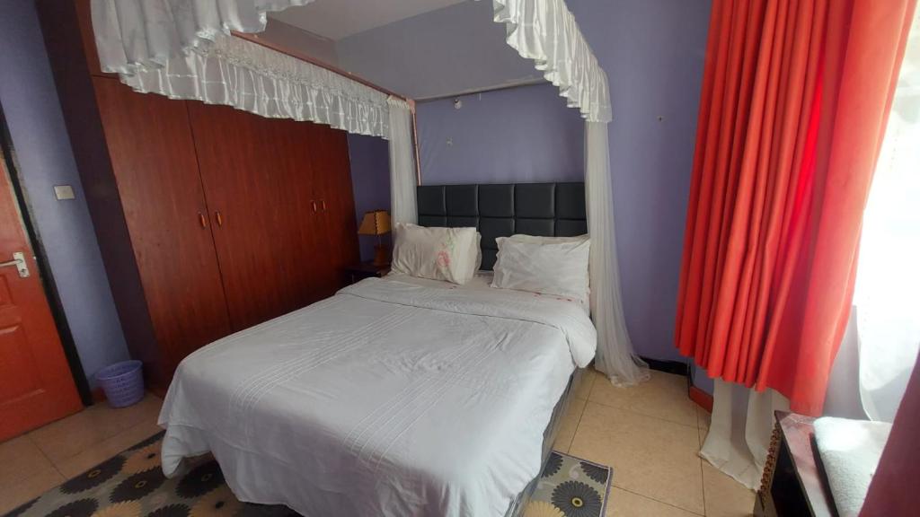 - une chambre avec un lit à baldaquin dans l'établissement Lux Suites Green City Gardens Syokimau, à Nairobi