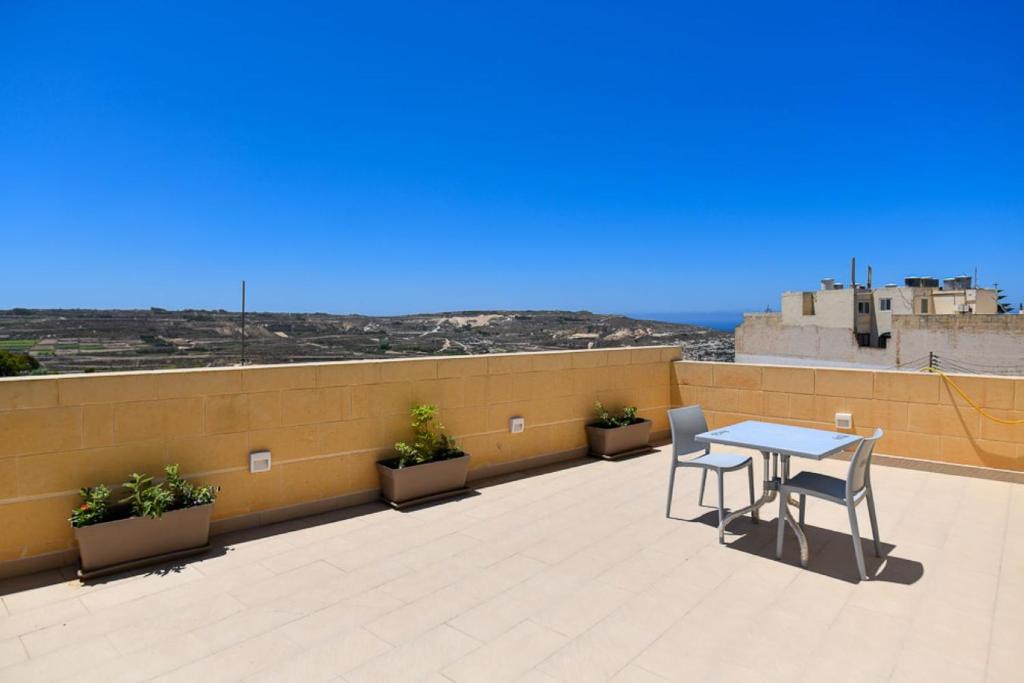 a patio with a table and chairs on a roof at Azure W B&B in San Lawrenz