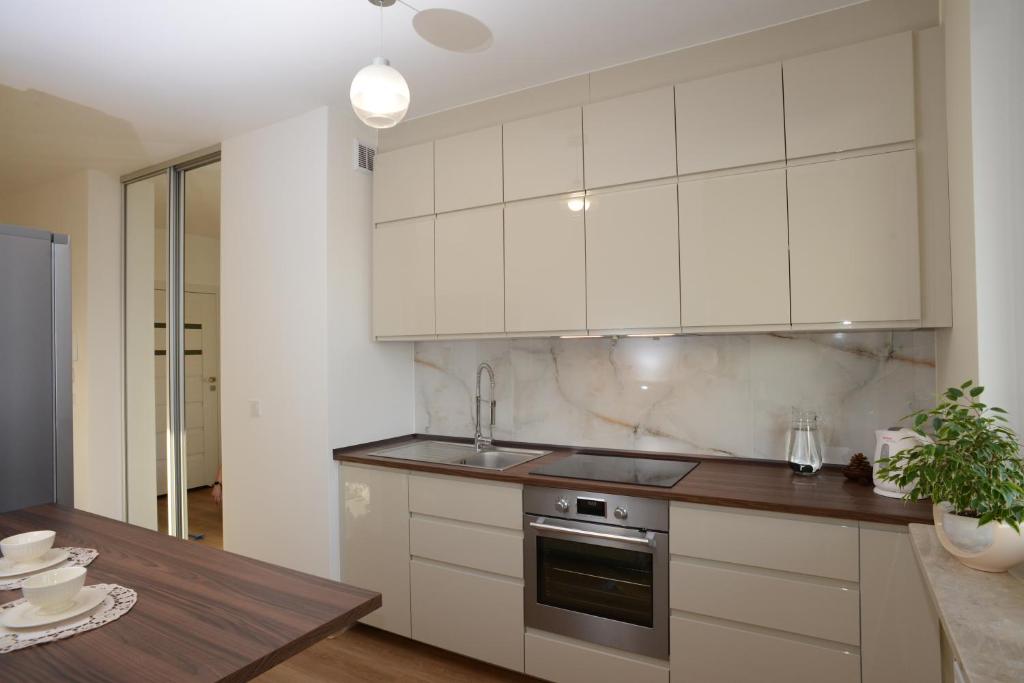 uma cozinha com armários brancos e uma mesa de madeira em Mieszkanie Zielony Targówek em Varsóvia