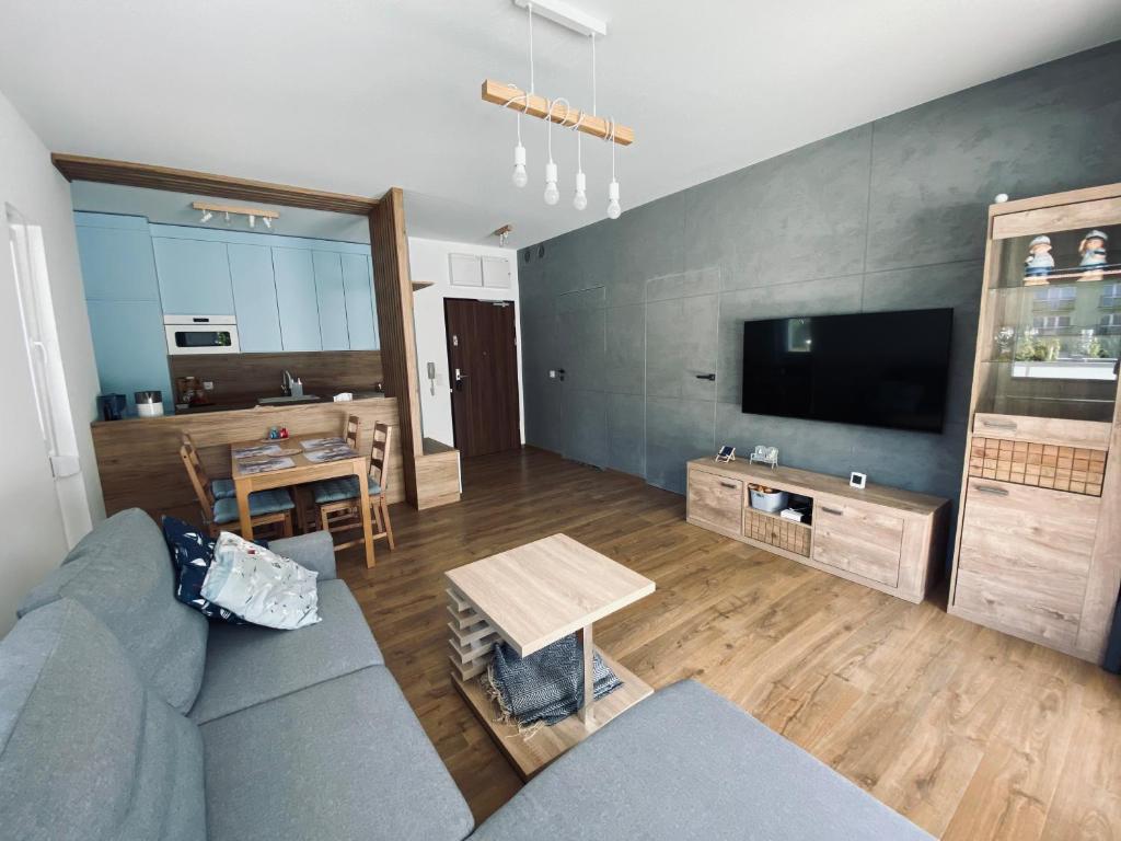 uma sala de estar com um sofá azul e uma televisão em Apartament Amilado em Pogorzelica