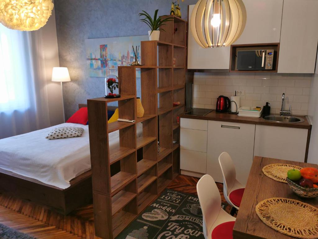 a bedroom with a bed and a kitchen with a table at Apartman Jovana 2 in Belgrade