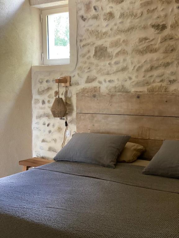 une chambre avec un lit avec un mur en pierre dans l'établissement Appartement Éden - campagne avec piscine commune - Eyragues, à Eyragues