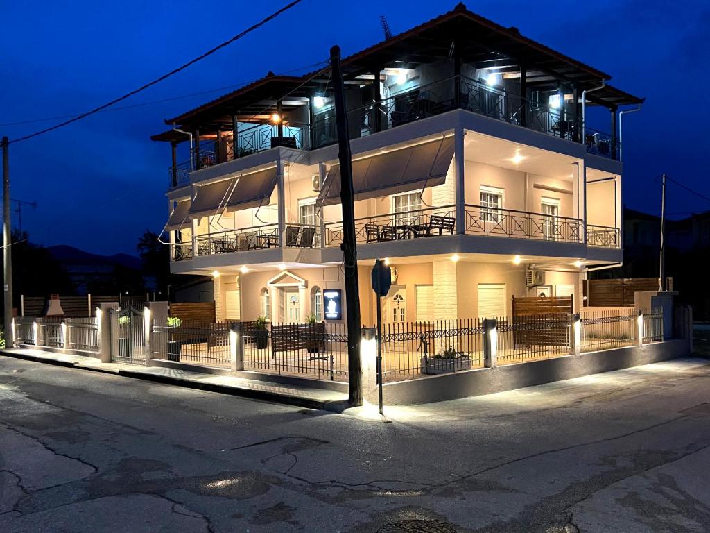 a large white building with a balcony at night at POSIDONIA RESORT No4 in Nea Vrasna