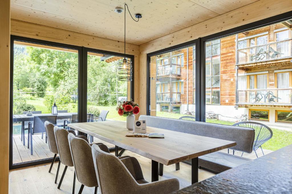 a dining room with a table and chairs and windows at Kreischberg Pool Villas by ALPS RESORTS in Sankt Lorenzen ob Murau