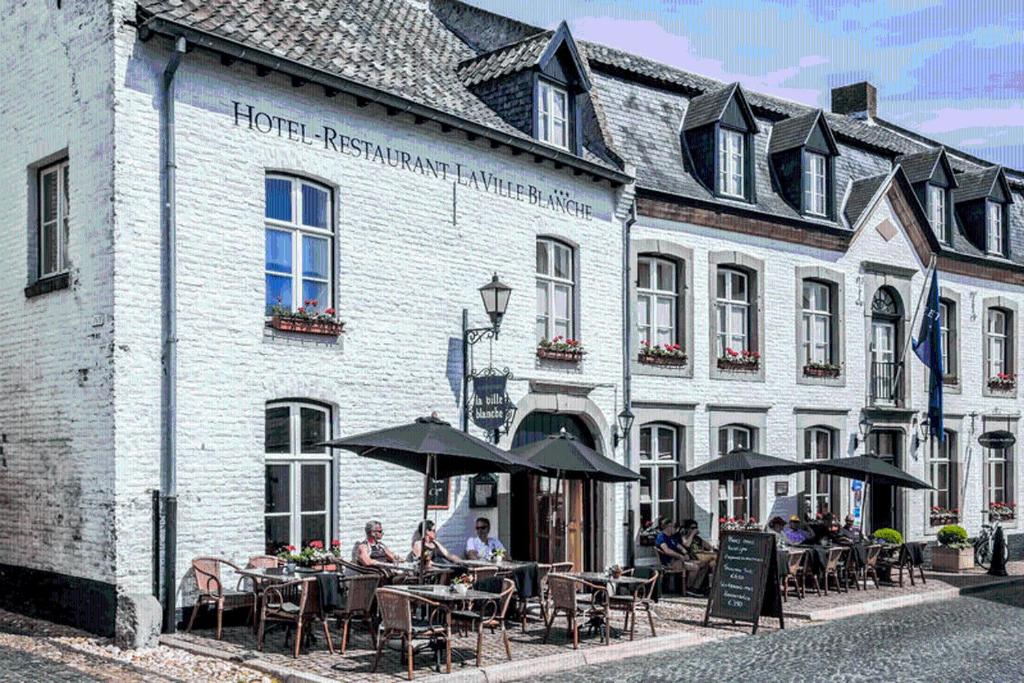 eine Gruppe von Personen, die außerhalb eines Gebäudes an Tischen sitzen in der Unterkunft Fletcher Hotel La Ville Blanche in Thorn