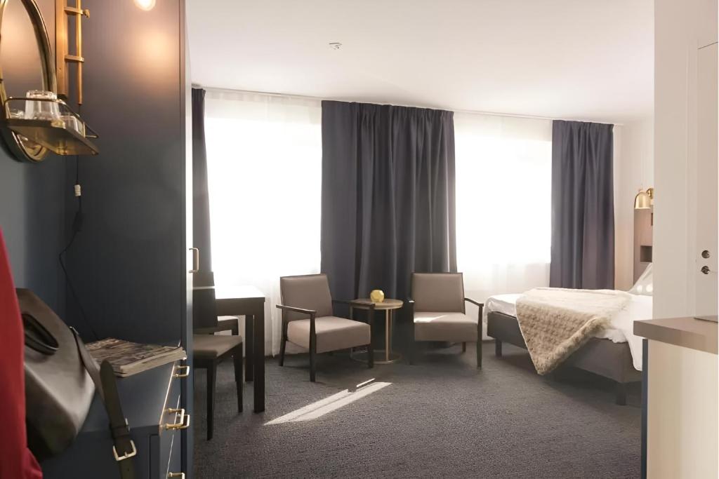 Habitación de hotel con cama, mesa y sillas en Communia Hotel Residence en Estocolmo
