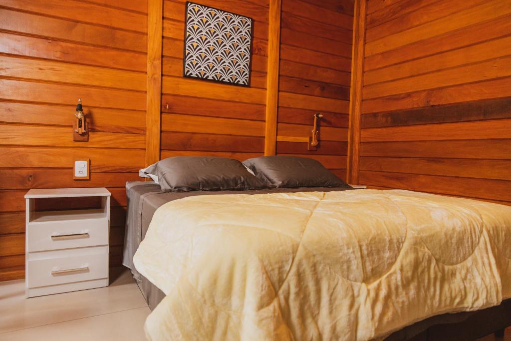 a bed in a room with wooden walls and wooden floors at Pousada Gagno in Domingos Martins
