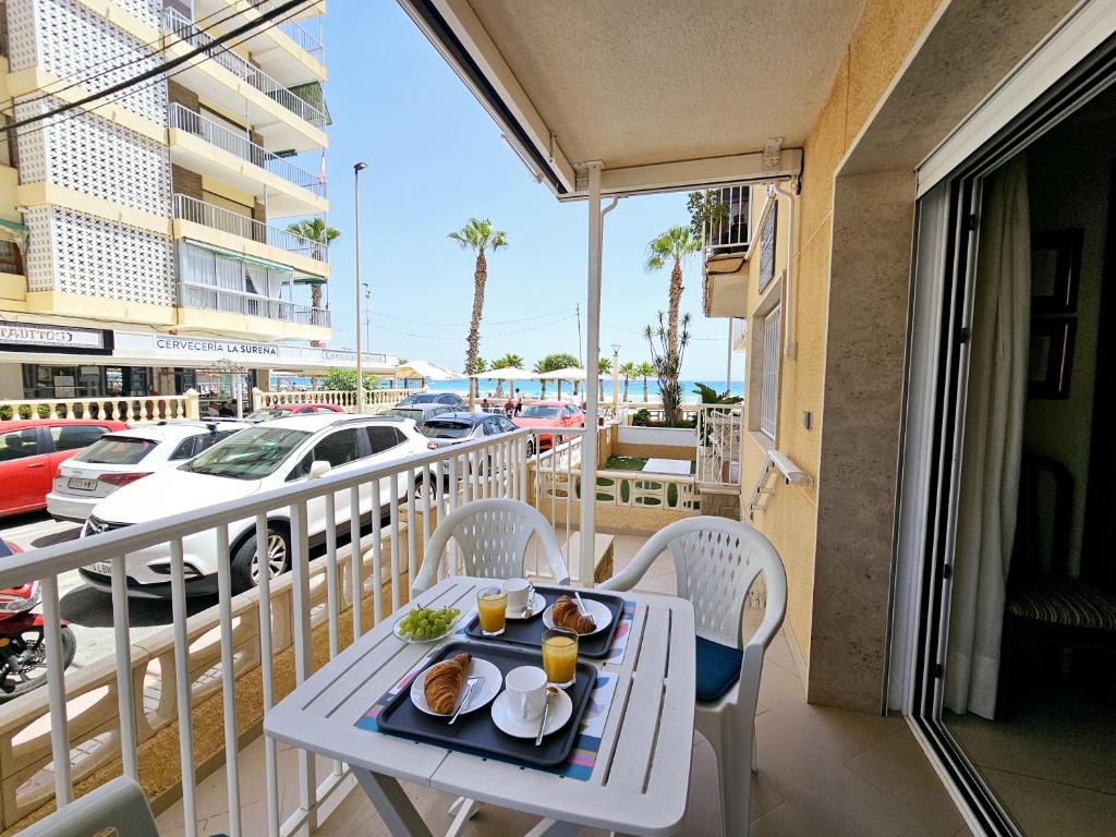 einen Tisch mit Tellern aus Essen auf einem Balkon in der Unterkunft Apartamento NEPTUNO - Primera Línea de Playa in El Campello