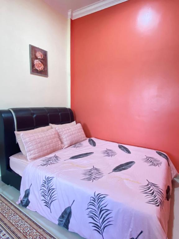 uma cama num quarto com uma parede vermelha em MNOOR HOMESTAY em Marang