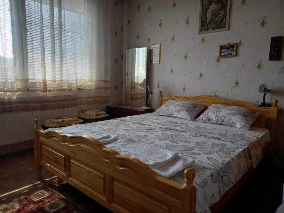 a bedroom with a large wooden bed with white sheets at Vintage Vibes - Family Flat in a Quiet Area in Sliven