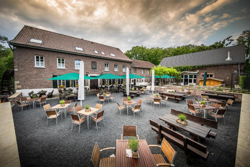 un patio al aire libre con mesas y sillas y un edificio en Die LÜ - Lüttelforster Mühle, en Schwalmtal