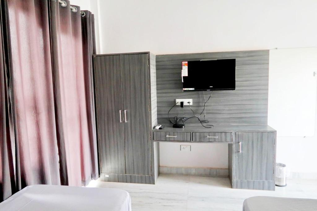 Habitación con escritorio y TV en la pared. en Aarambh Residency en Khajurāho